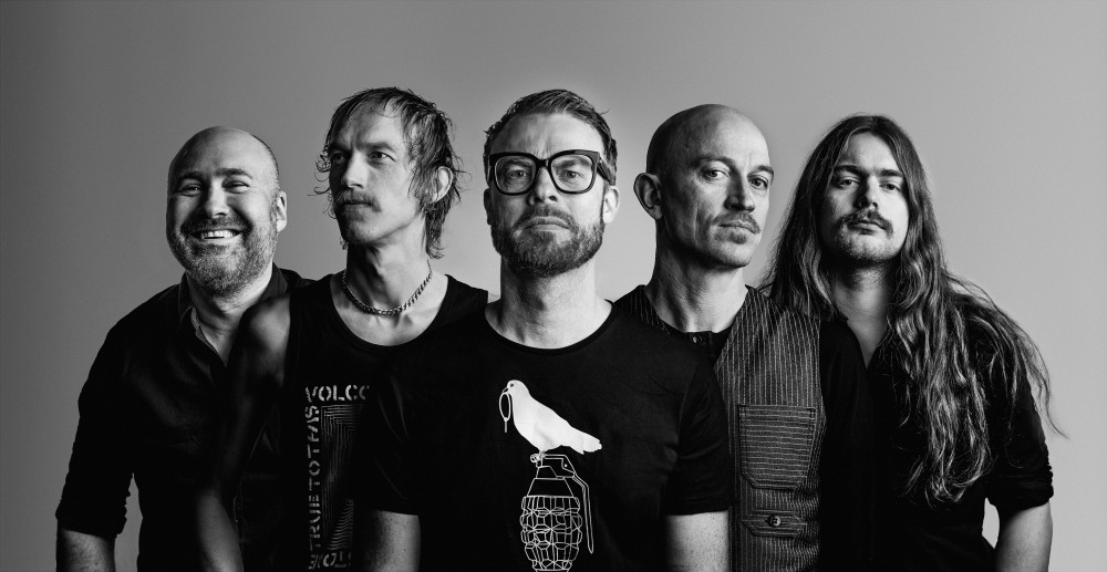 Schwarz/weiß Fotografie der Band Spidergawd: Fünf männlich gelesene Personen, abgebildet ist nur der Oberkörper, blicken in die Kamera. Alle sind schwarz gekleidet.