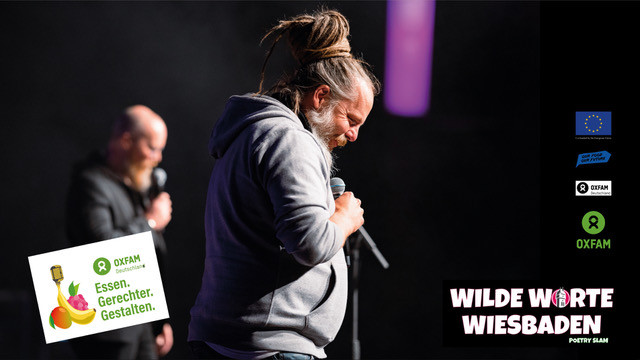 Es ist eine männlich gelesene Personen vor einem dunklen Hintergrund zu sehen. Sie trägt einen grauen Kapuzenpullover, einen grauen Bart und zu einem Dutt geflochtene Dreadlocks. In der rechten unteren Ecke des Bildes ist der weißer Schriftzug "WILDE WORTE WIESBADEN" zu lesen.