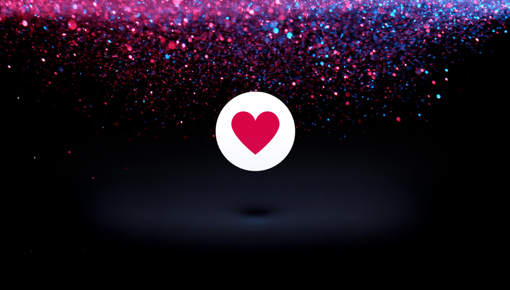 Der Hintergrumd ist dunkel. Oben im Hintergrund ist Glitzer zu sehen. In der Mitte des Bildes ist ein Herz zu sehen.