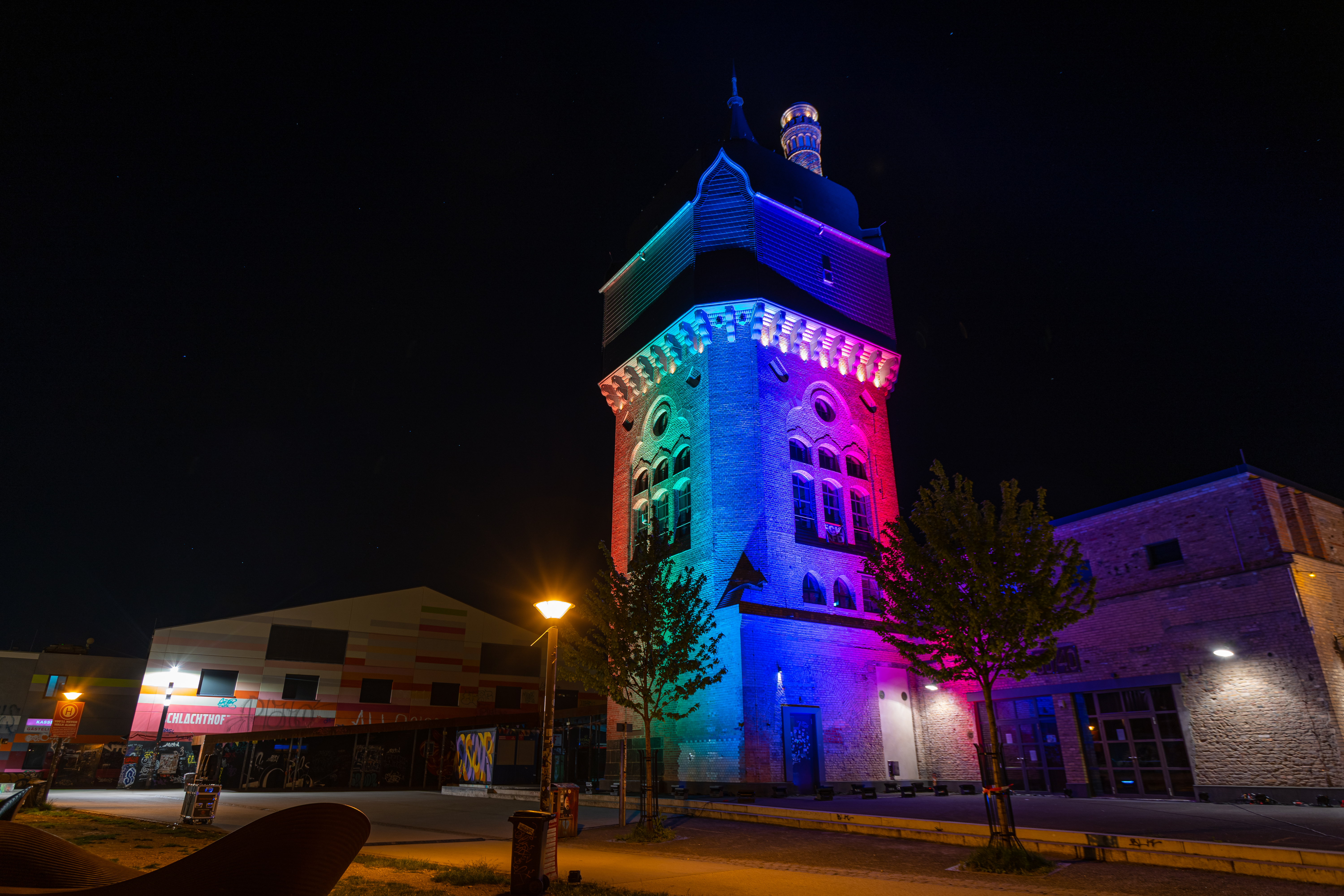 Nachtbild des Wasserturms des Kulturzentrums Wiesbaden mit regenbogenfarbenen Lichtern angestrahlt